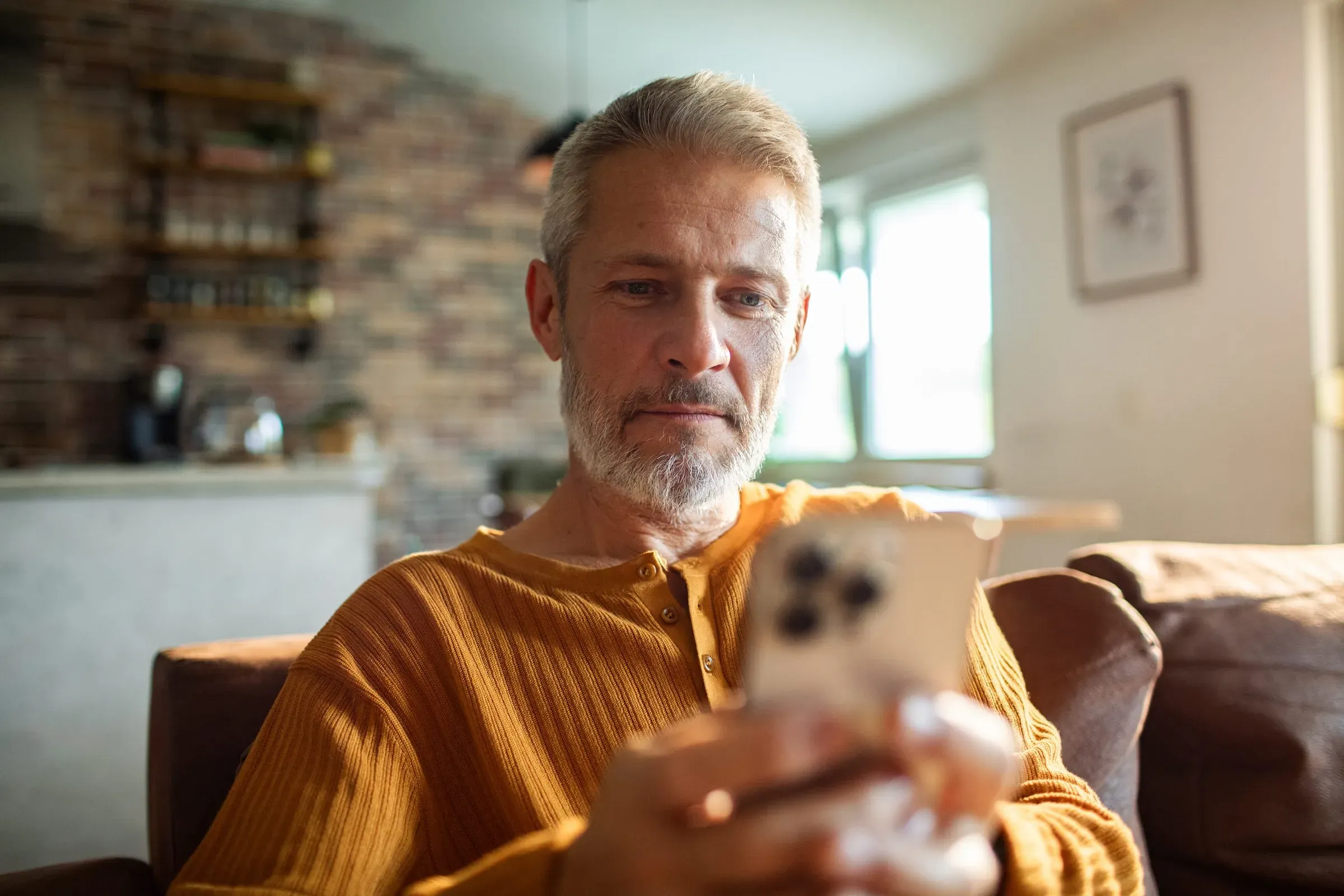 An older man at home looking at his phone, content