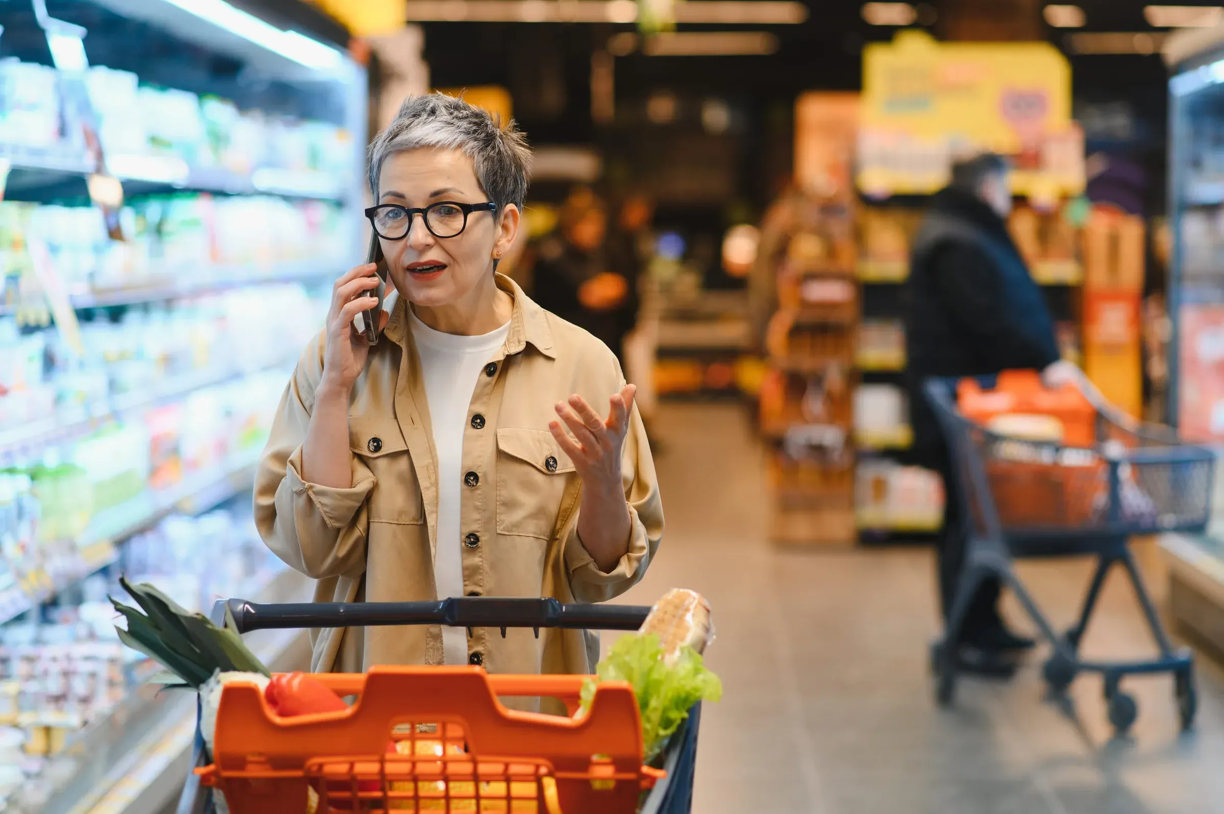 An older woman in a supermarket talking on the phone while shopping