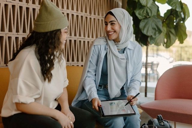 Two people talking outdoors about something on a tablet screen